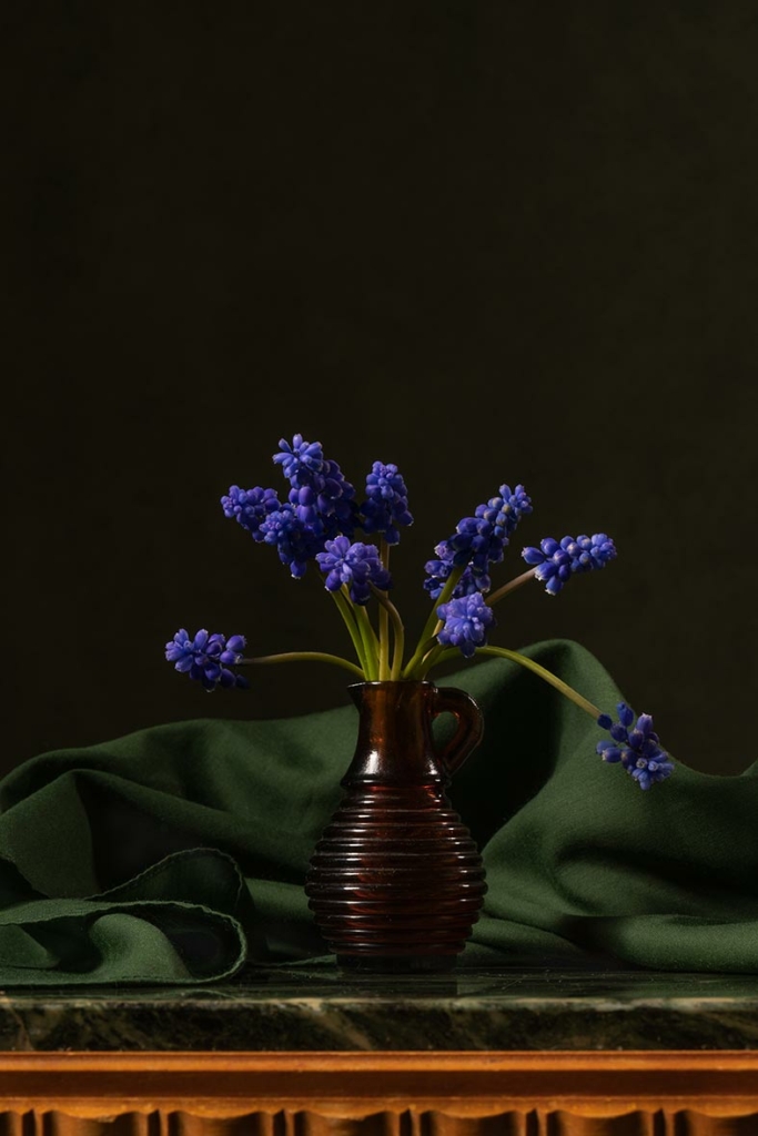 A purple flower arranged in a vase on green fabric. Branding & web design. House of Hyacinth - Visual Design Studio.